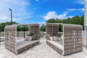 Two outdoor seating areas with woven privacy screens, cushioned benches, and a paved floor.