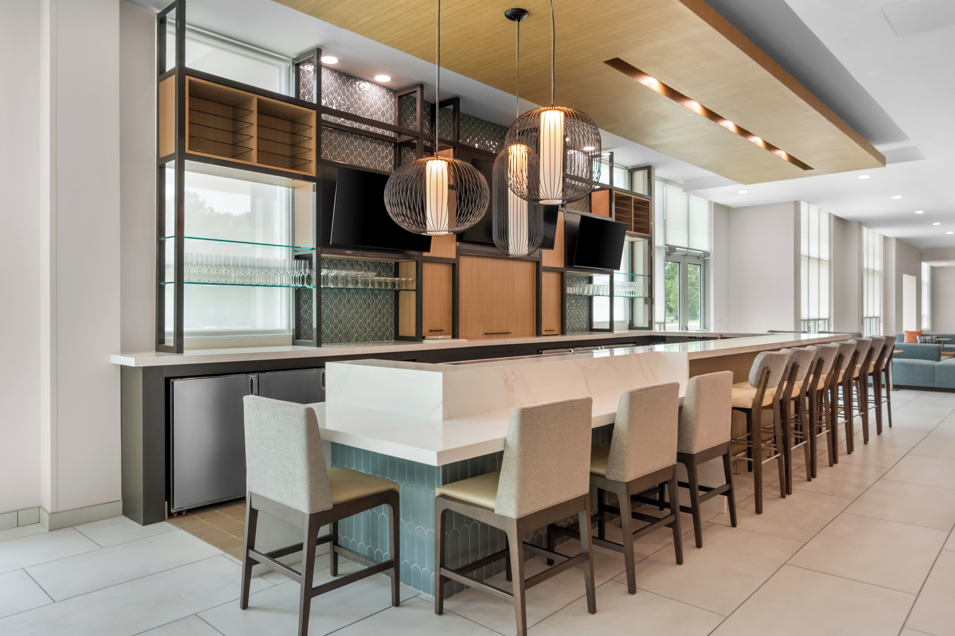 Una cocina moderna con una isla central, taburetes de bar e iluminación colgante.