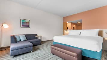 Una habitación de hotel con cama, sofá, banco, escritorio y lámpara.