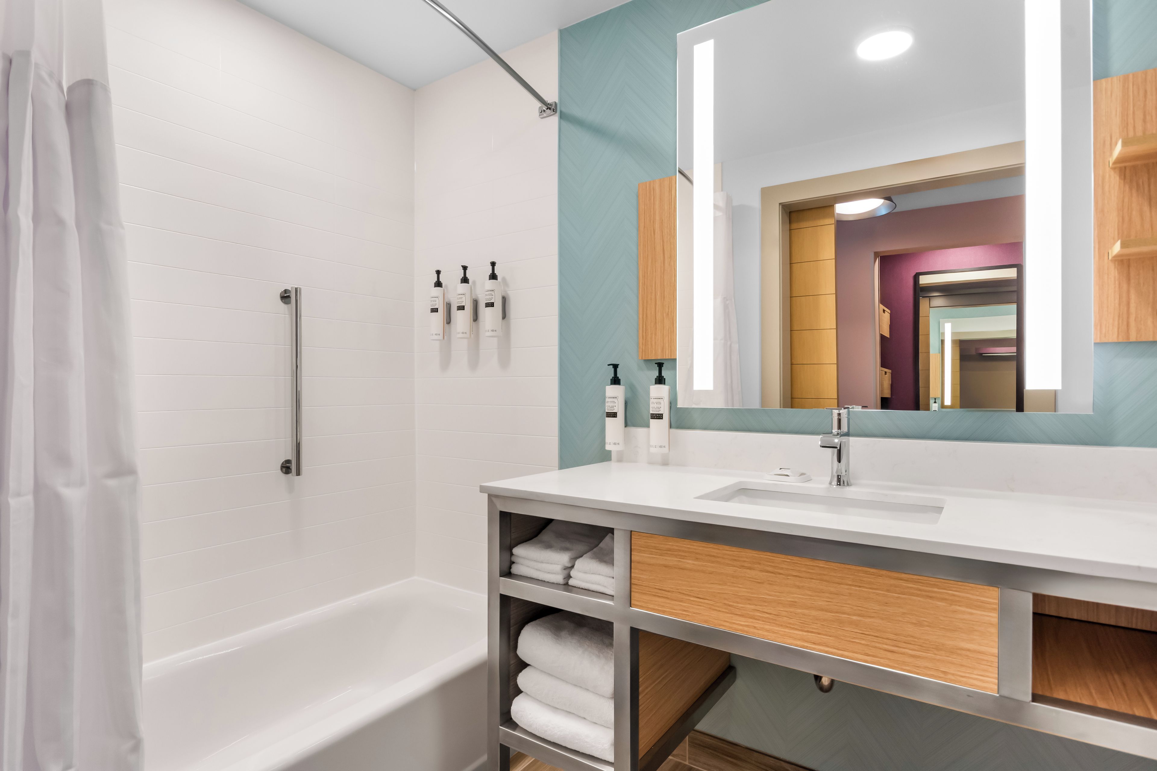 A modern bathroom with a white bathtub, a large mirror, and a vanity with a sink.