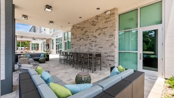 An outdoor patio area with a stone wall, seating, and a bar.