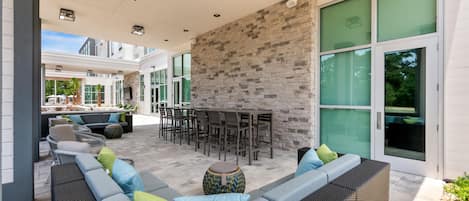 An outdoor patio area with a stone wall, seating, and a bar.