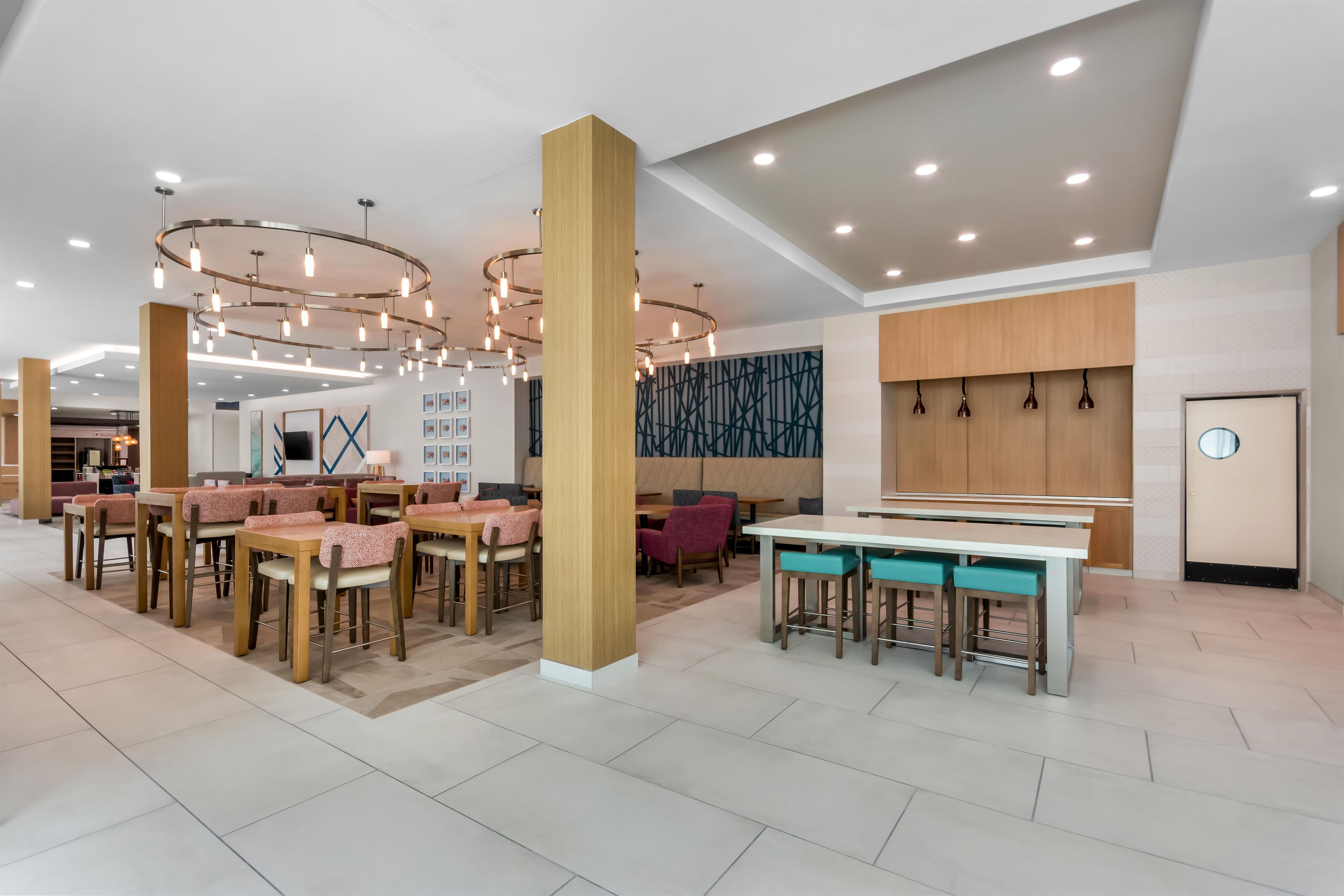 A modern interior with multiple seating areas, including tables and chairs, and a central bar area.