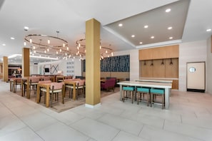 A modern interior with multiple seating areas, including tables and chairs, and a central bar area. - Hilton Garden Inn Destin Commons (Destin)
