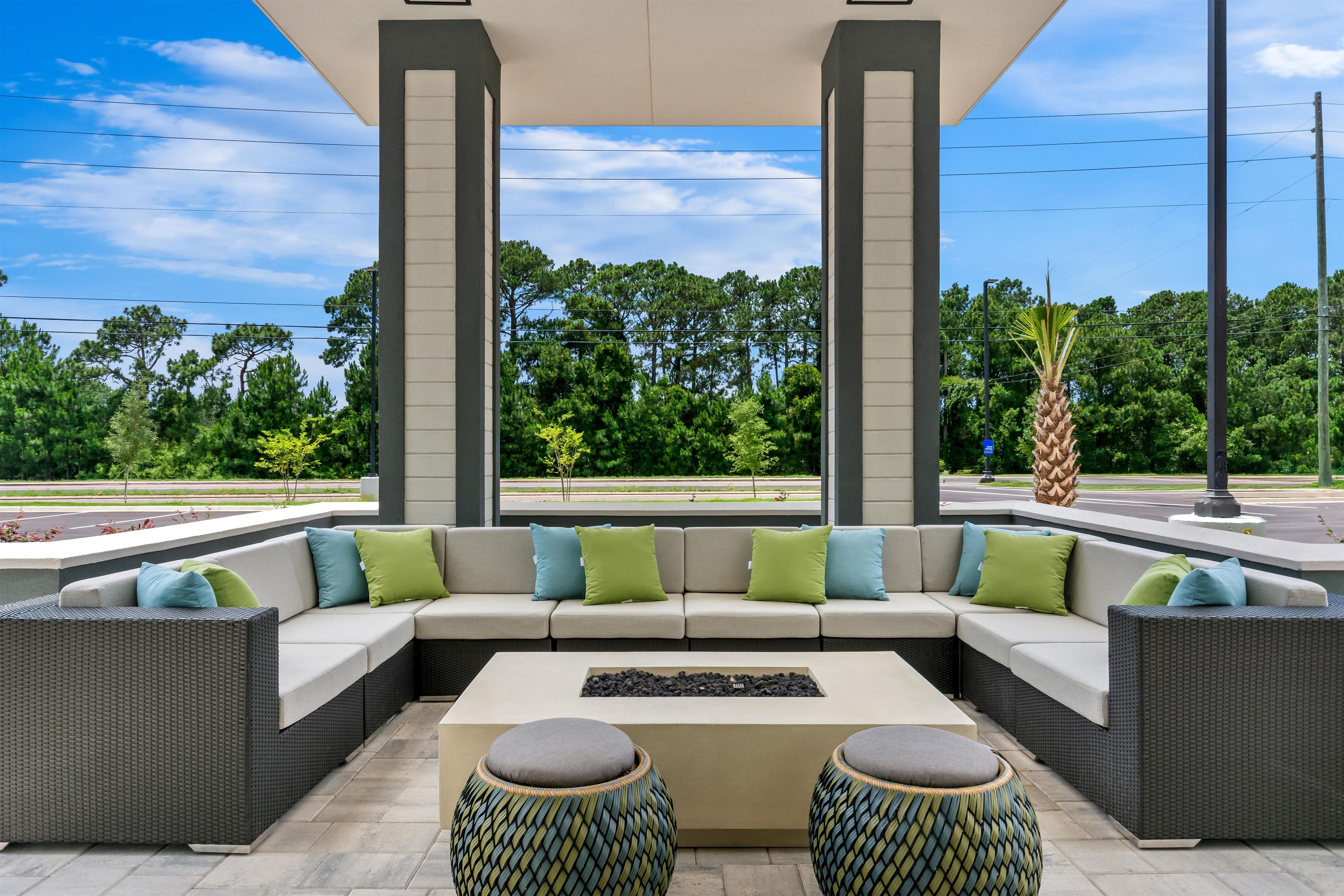 An outdoor seating area with a sectional sofa, two round ottomans, and a coffee table.