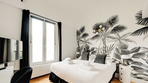 A hotel room with a bed, a desk, a TV, and a window with curtains. - Spacious Appartement 2BR/7P - Nogent-sur-Marne (Nogent-sur-Marne)