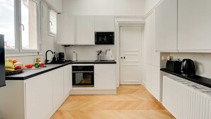 A modern kitchen with white cabinets, a black countertop, a dishwasher, and a window with a city view. - Spacious Appartement 2BR/7P - Nogent-sur-Marne (Nogent-sur-Marne)