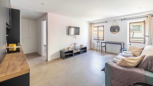 Un salon moderne comprenant un canapé, un téléviseur, un coin repas et une cuisine.