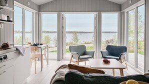 Cozinha moderna com vista para um lago, área de refeições com cadeiras e um sofá.
