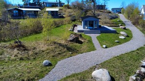 Una zona residencial con casas, un sendero de grava y una pequeña construcción con puertas de vidrio.
