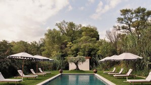 A pool with lounge chairs and umbrellas, surrounded by greenery. - Luxury Provençal house – Pool, nature & spa (Villes-sur-Auzon)