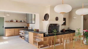A modern kitchen with wooden cabinets, a central island, and pendant lighting. - Luxury Provençal house – Pool, nature & spa (Villes-sur-Auzon)