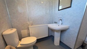Un baño con inodoro, lavabo, radiador y espejo.