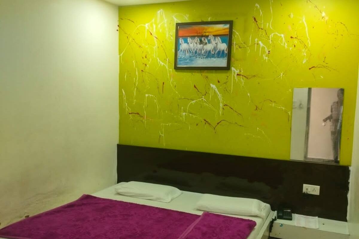 A bedroom with a bed, a headboard, a wall with a painting, a ceiling fan, and a window.
