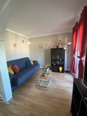 A living room with a sofa, a coffee table, a bookshelf, and a lamp. - La Riviera T3 apartment (Saint-Raphaël)