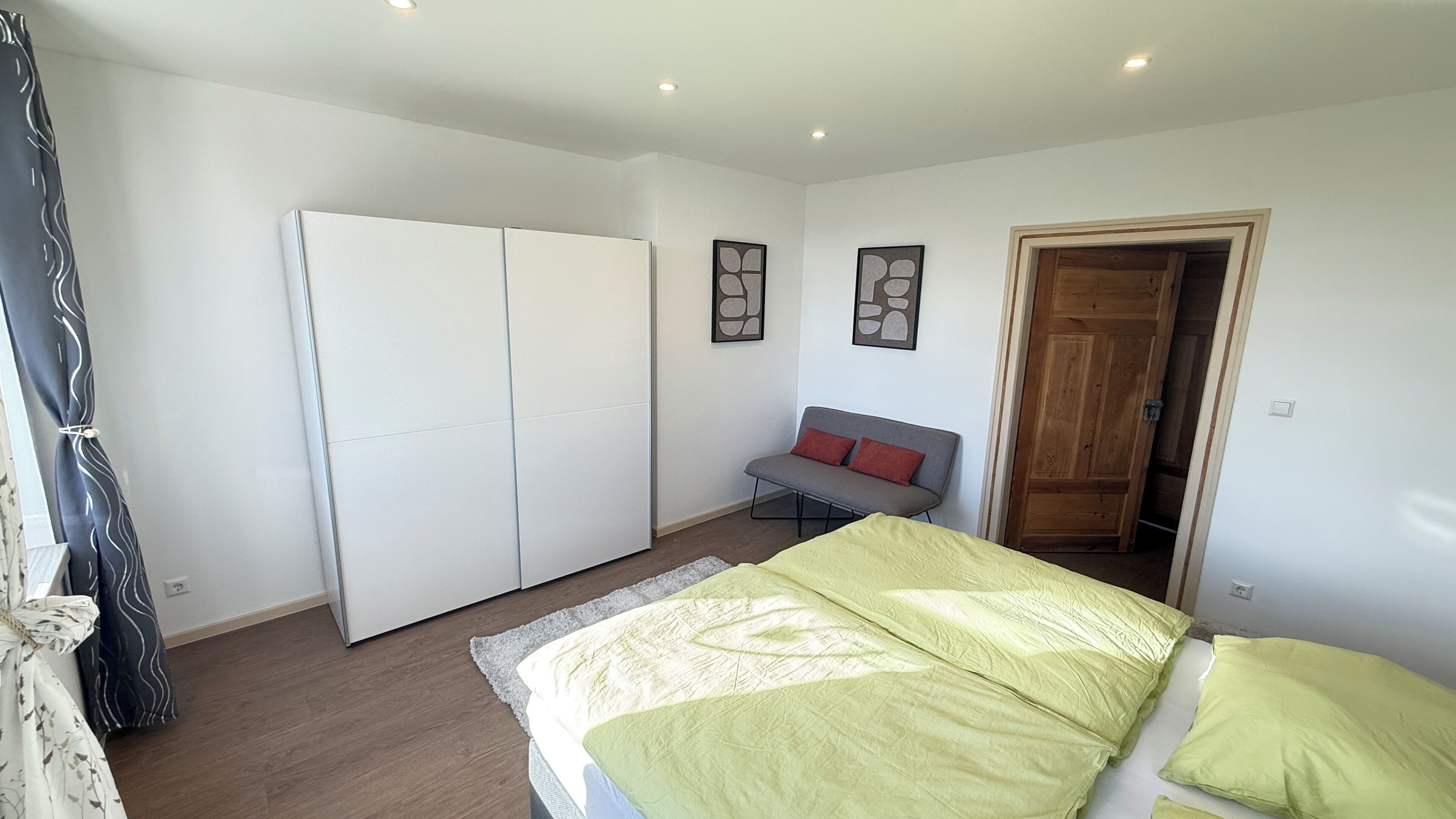 Un dormitorio con cama, sofá, armario y puerta.