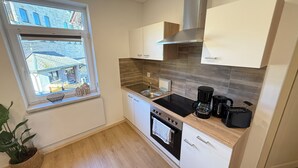 A compact kitchen with a window, a stove, a sink, and a coffee maker.