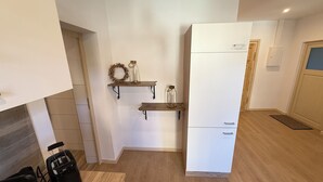 A kitchen with white cabinets, wooden shelves, and a refrigerator.