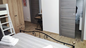A bedroom with a bed, a wardrobe, a desk, and a bathroom visible through an open door. - 50 special apartment (Pontedera)