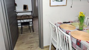 A dining area with a table set for two, a framed picture on the wall, and a TV mounted above the table. - 50 special apartment (Pontedera)