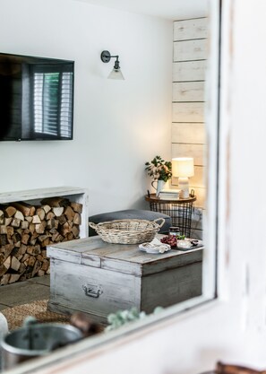 Ein gemütliches Wohnzimmer mit Kamin, Fernseher, Lampe und einem Essbereich mit Tisch und Stühlen.