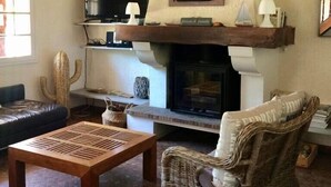 Ein gemütliches Wohnzimmer mit Kamin, bequemen Sitzmöglichkeiten und einem Fernseher.