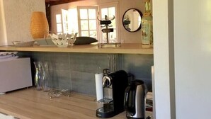 Eine Küche mit Holzbalken, einer Kaffeemaschine, einem Wasserkocher und einer Flasche auf der Arbeitsplatte.