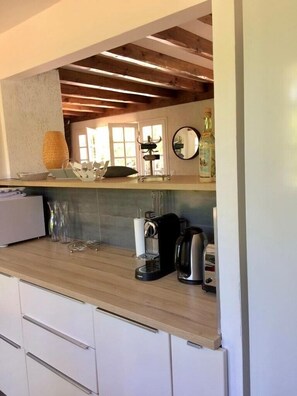 Eine Küche mit Holzbalken, einer Kaffeemaschine, einem Wasserkocher und einer Flasche auf der Arbeitsplatte.