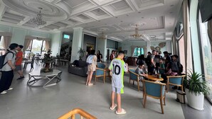 A spacious lobby with a high ceiling, multiple seating areas, and a large window providing natural light.