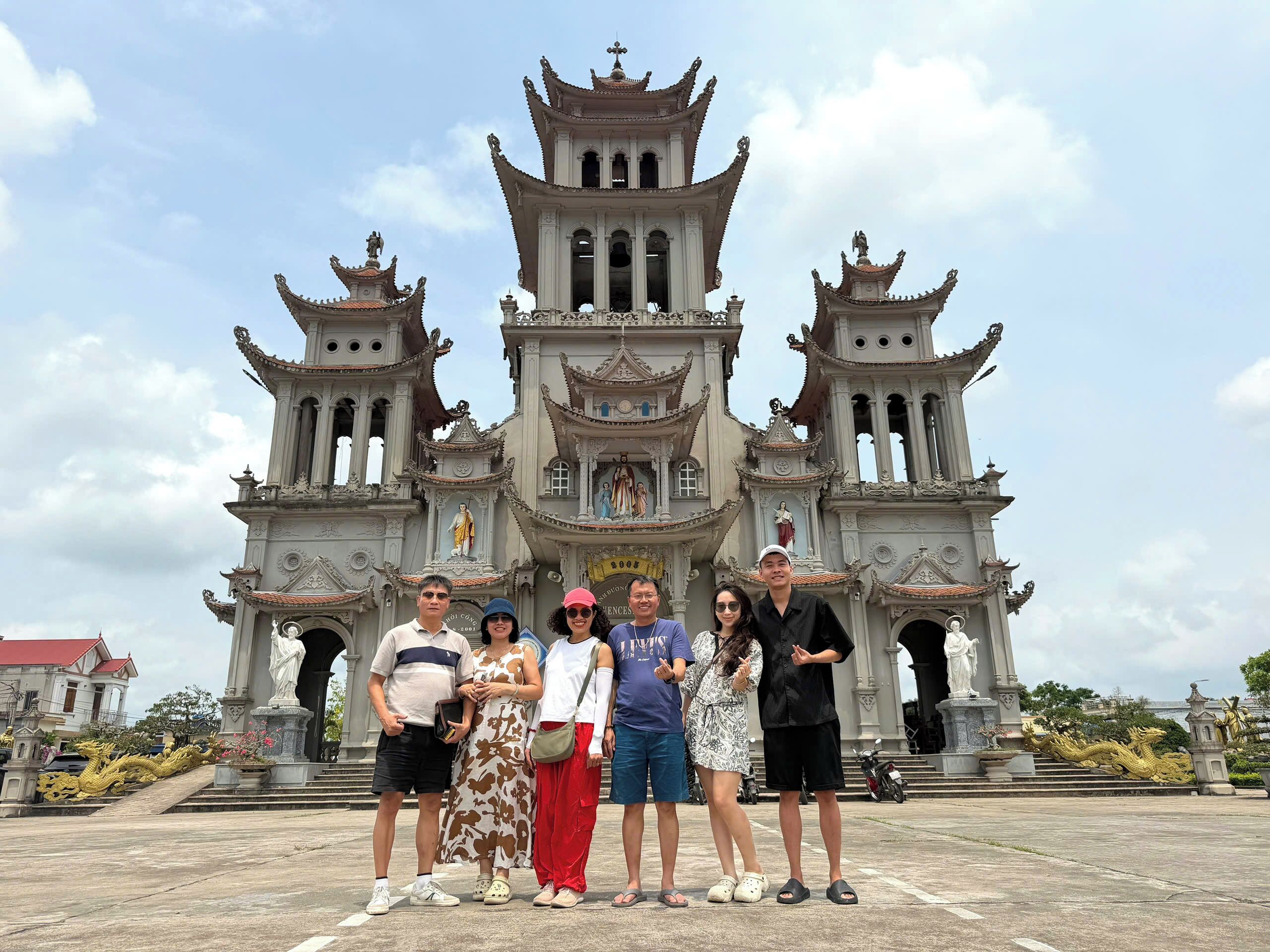 A group of people standing in front of a large, ornate building with multiple towers and statues.