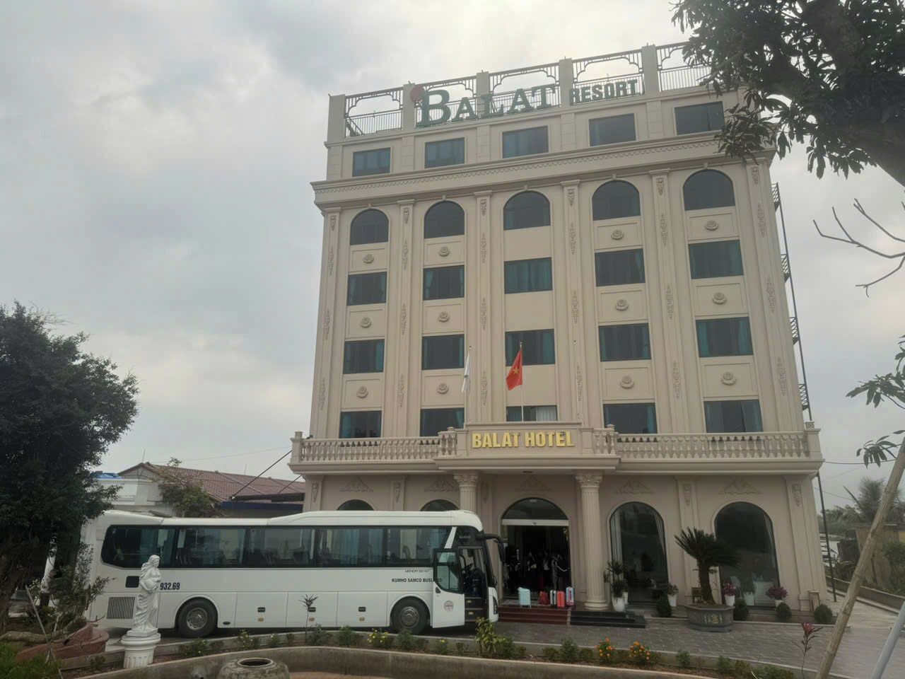 Een groot gebouw met een bord waarop 'Balai Hotel' staat en een vlag.