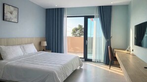 A hotel room with a bed, a desk, a chair, a TV, and a balcony with curtains.