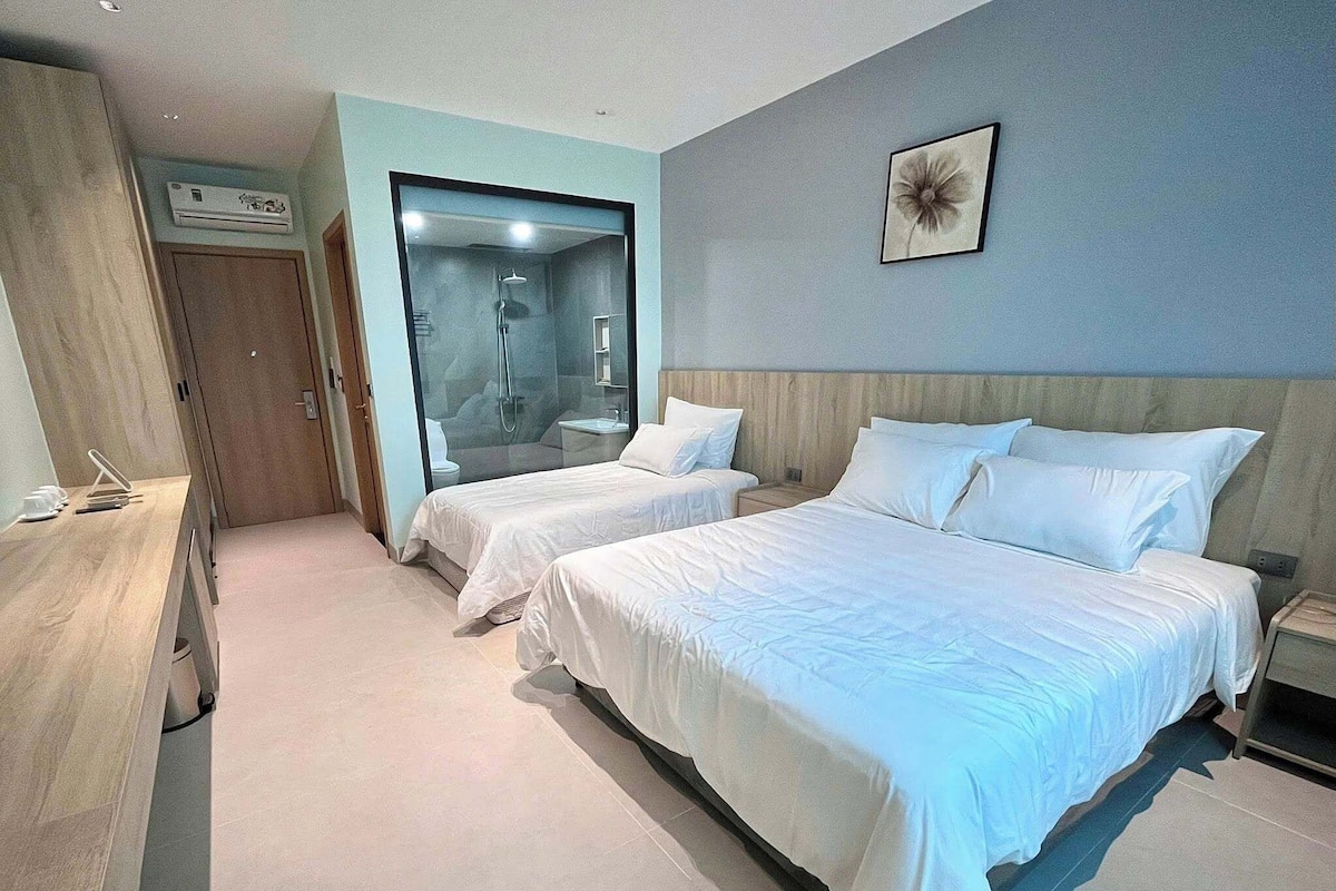Ein Hotelzimmer mit zwei Betten, einer Dusche, einem Holzschrank und einem an der Wand hängenden Bild.