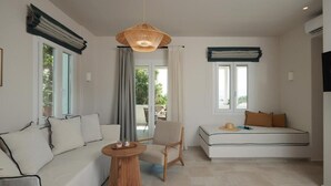 Ein modernes Wohnzimmer mit einer Couch, einem Sessel, einem runden Tisch und einer Pendelleuchte.