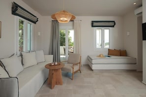 Una sala de estar moderna con un sofá, una silla, una mesa redonda y una lámpara colgante.