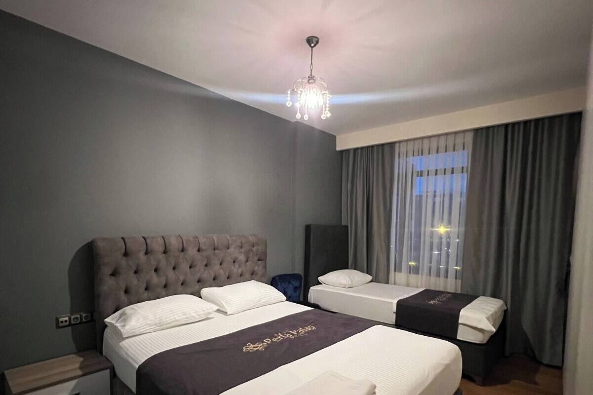 A modern hotel room with a large bed, a smaller bed, a desk, and a chair.