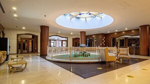 A hotel lobby with a central fountain, seating areas, and a skylight.