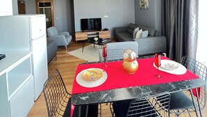 A modern living space with a dining area, kitchen, and seating area. - ELİT PERLA SUIT (İstanbul)