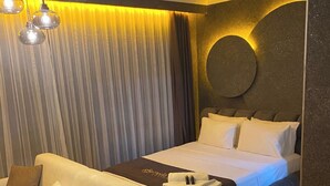 A hotel room with a bed, a sofa, a bedside table, and a circular wall decoration.