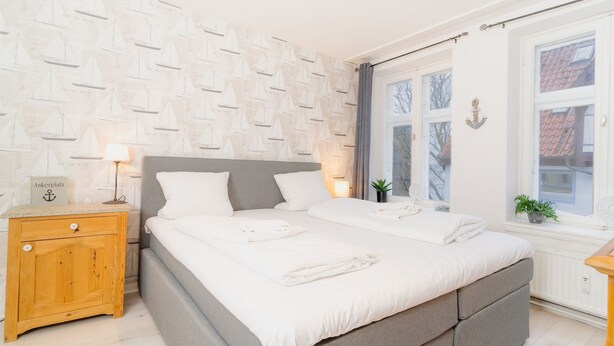 Een slaapkamer met een bed, nachtkastje en raam.