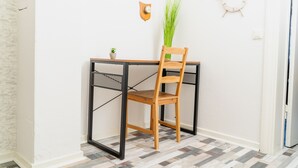 A corner room with a wooden chair, a small table, a potted plant, and a wall clock. - fewo1846 - Pirate's Cabin / Centrally Located Apartment in an Older Building for Up to 4 People (Flensburg)