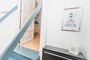 A staircase with blue steps leading to a room. A framed sign with a lighthouse and the text 'HEIMAT HAFEN' is on the wall. - fewo1846 - Sternkoje - ideal for a relaxing break for two in the city center (Flensburg)