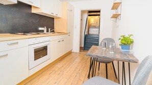 Una cocina compacta con armarios blancos, encimera de madera y horno empotrado.