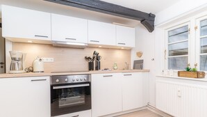 A modern kitchen with white cabinets, a built-in oven, a coffee maker, and a window with a view.