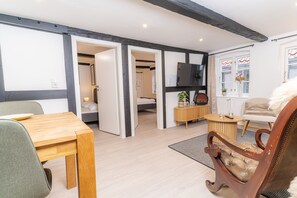 Ein modernes Wohnzimmer mit einem Holztisch, einem Ledersessel und einem an der Wand montierten Fernseher.