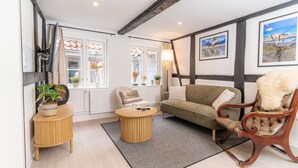 A cozy living room with a sofa, a chair, a small round table, and a window with curtains.