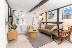 A cozy living room with a sofa, a chair, a small round table, and a window with curtains. - fewo1846 - Zeppelin berth (Flensburg)