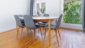 Un comedor con una mesa redonda, cuatro sillas y vista a follaje a través de una ventana.