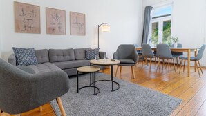 Una sala de estar moderna con un sofá gris, una mesa de centro redonda y un comedor con sillas y una mesa.