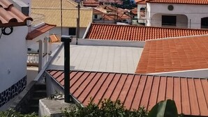 Uma área residencial costeira com telhados de terracota, céu limpo e vista distante do mar.